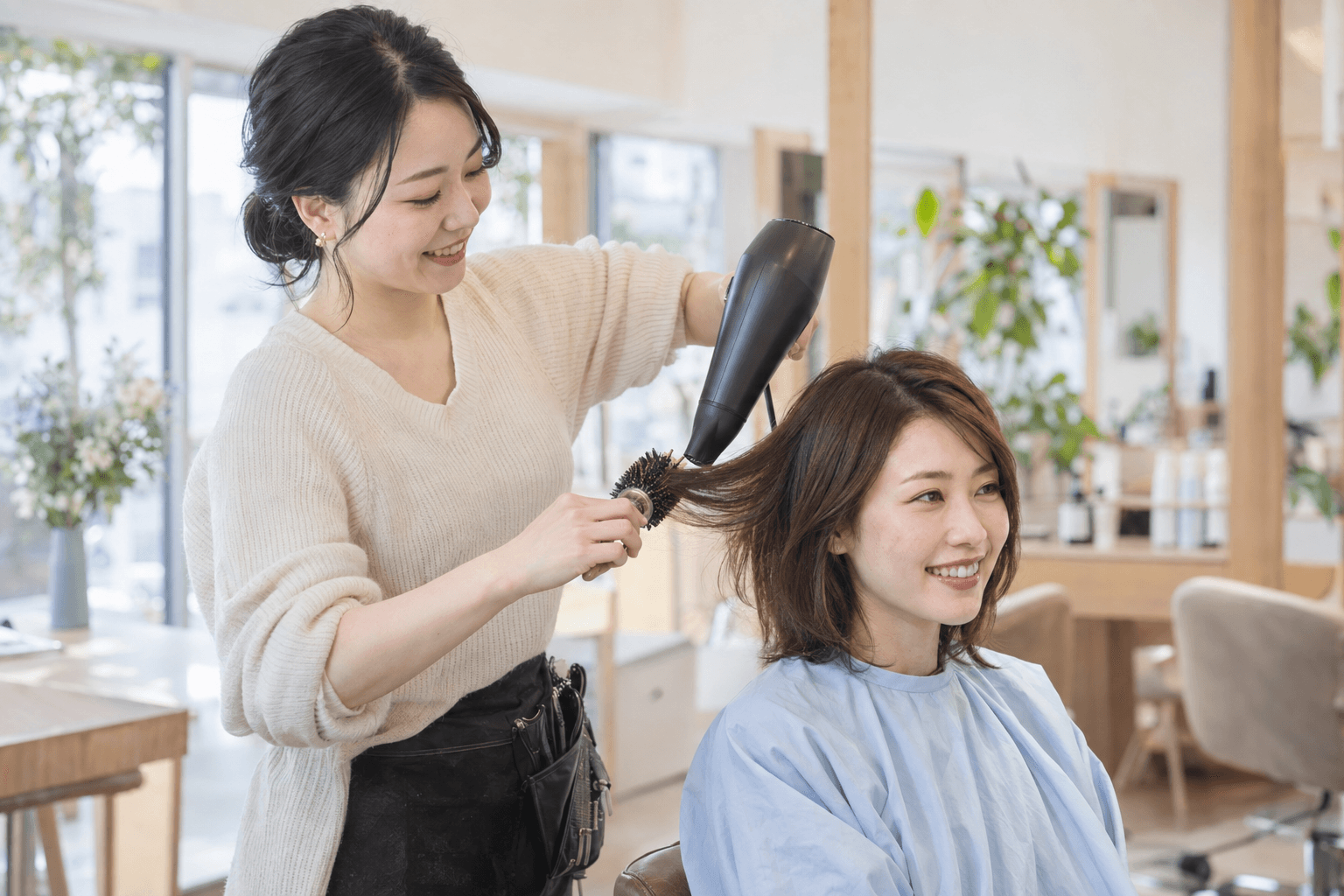 ブラシとドライヤーでお客様の髪を仕上げる美容師