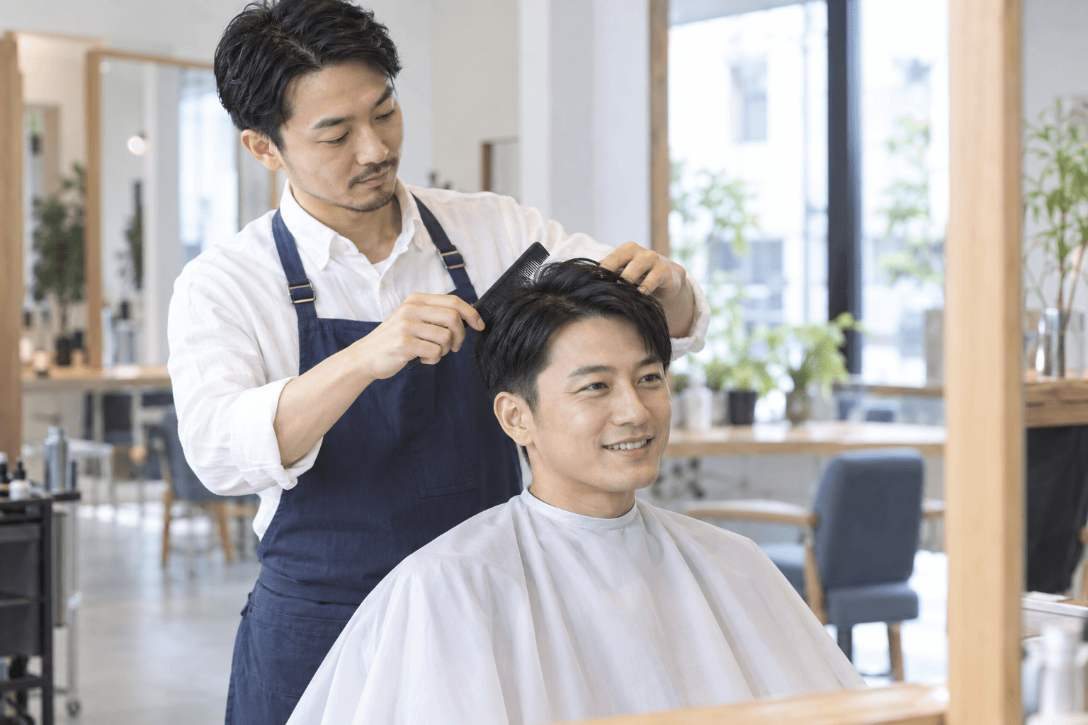 男性のお客様のヘアスタイルをコームで整える美容師